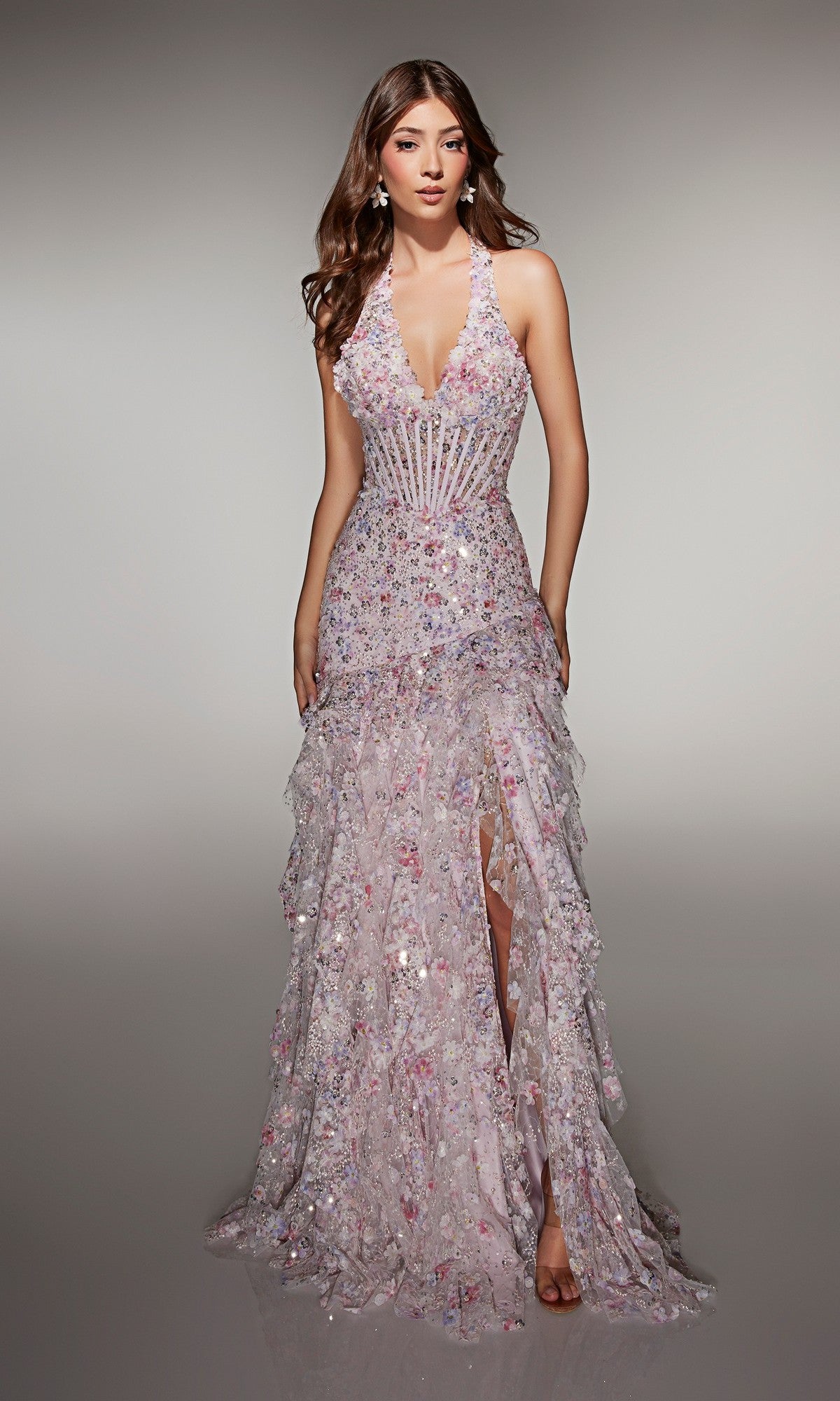 A woman wearing the Alyce 61999 long prom dress—light pink, floor-length, sleeveless halter style with sequin embellishments, a fitted corset bodice, a ruffled skirt, and a high slit.